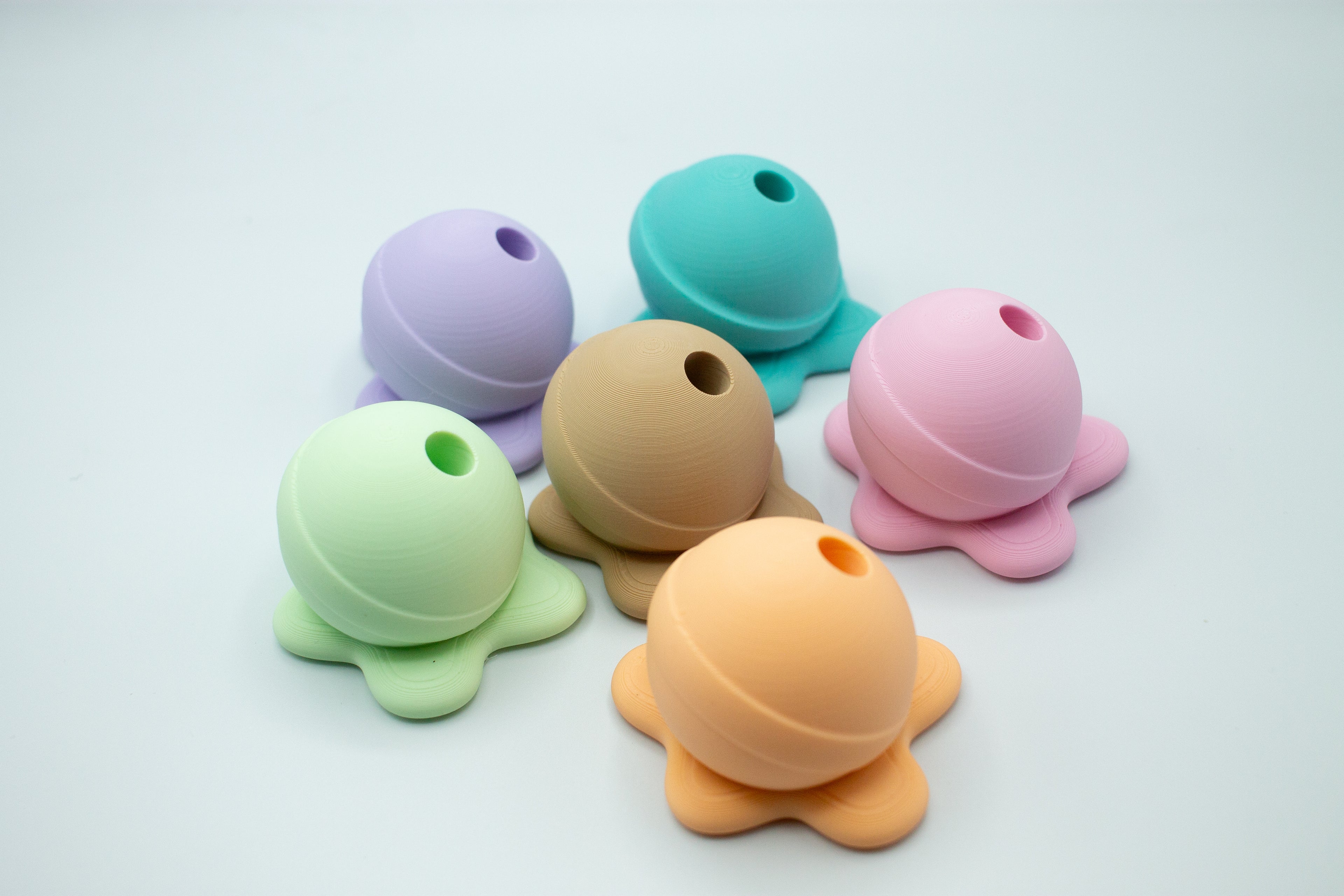 Set of colorful apple pencil holder shaped like a melted lollipop on a light gray background