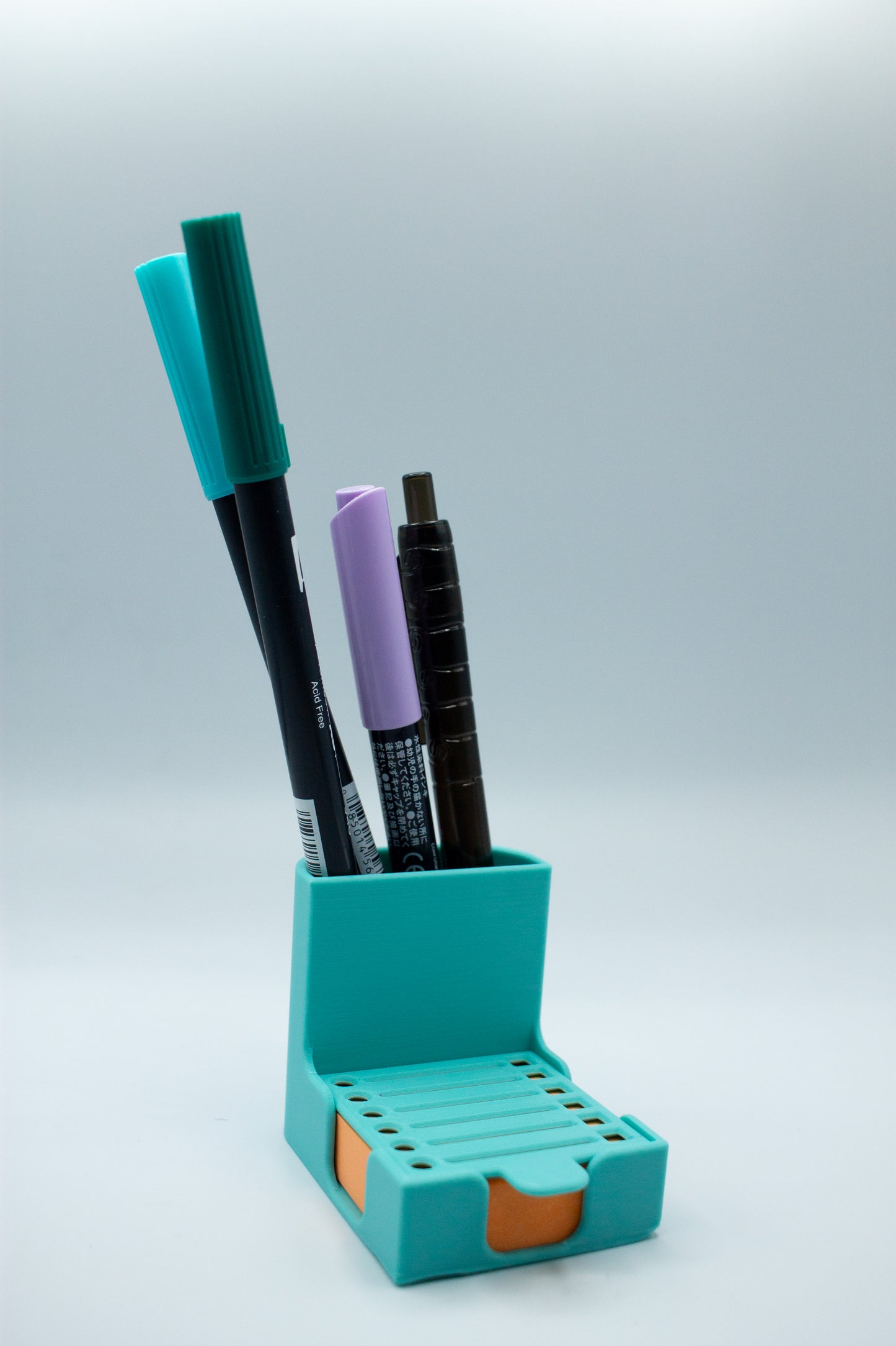 Turquoise pen holder with markers on a light gray background
