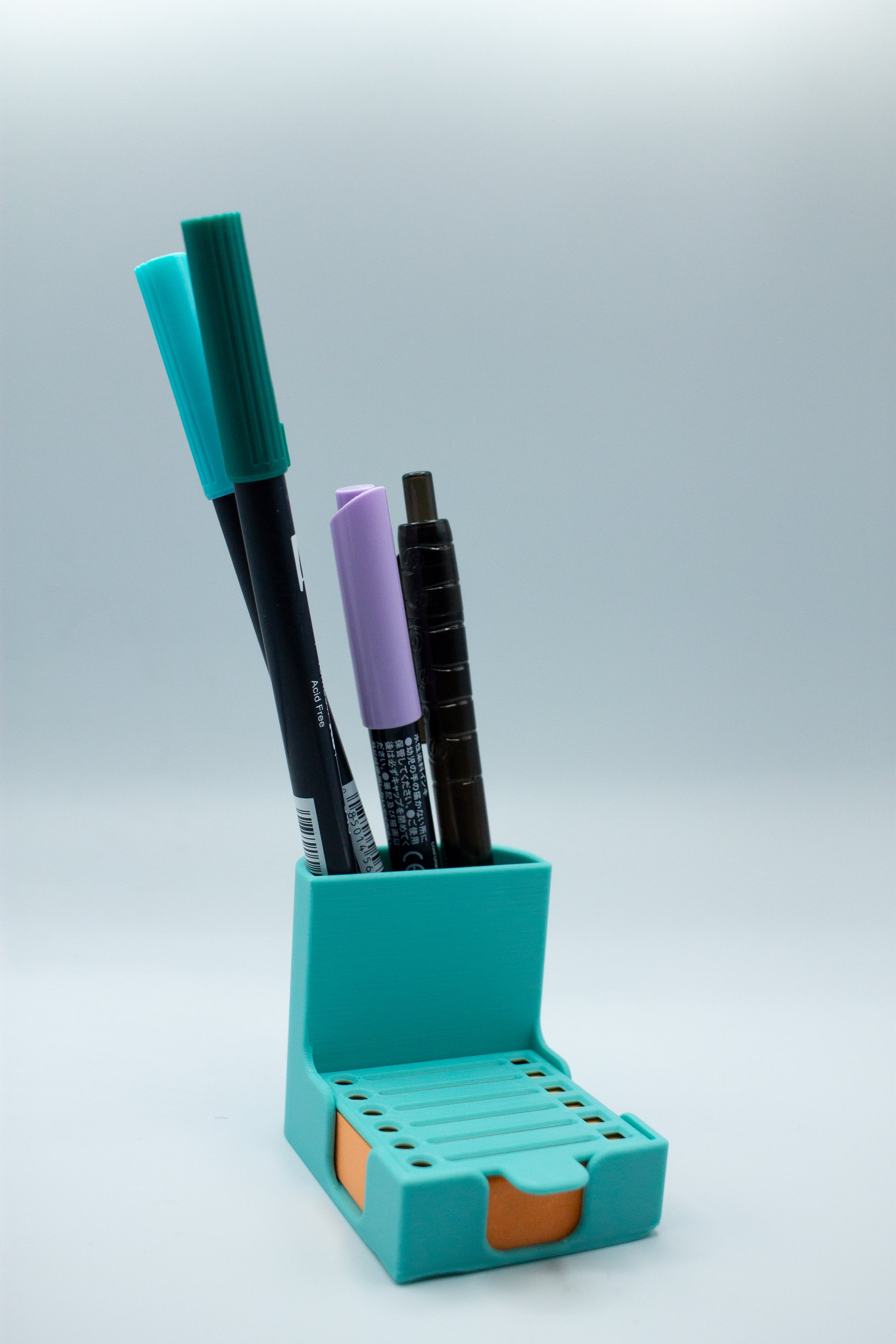 Turquoise pen holder with markers on a light gray background